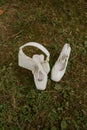 Pair of white bridal high-heeled shoes on a patch of grass