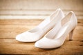 Pair of White Bridal Shoes on Rustic Wood Floor