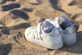 A pair of white children\'s sneakers on the beach sand Royalty Free Stock Photo