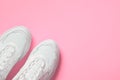 Pair of white female trendy sneakers on pink. Flat lay, top view minimal background