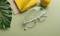 pair white-framed glasses rests on green surface, accompanied by yellow notebook, green leaf, and small Royalty Free Stock Photo
