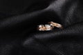 Pair of white gold wedding rings with pink gold knot on black le