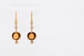 Pair of white golden diamond earrings with orange citrine or sapphire on transparent stand. Golden earrings with