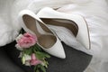 Pair of white high heel shoes, flowers and wedding dress on chair Royalty Free Stock Photo
