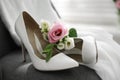 Pair of white high heel shoes, flowers and wedding dress on chair indoors, closeup Royalty Free Stock Photo