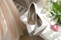 Pair of white high heel shoes, flowers and wedding dress indoors Royalty Free Stock Photo