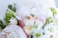 Two designer wedding rings, one in white gold with diamonds, are placed on the bride`s bouquet of white and pink roses Royalty Free Stock Photo