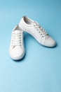 Pair of white sneakers on blue background. Fashion blog or magazine concept Royalty Free Stock Photo