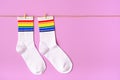 Pair of white socks with rainbow edging on pink background