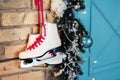 Pair of white vintage leather skates with red laces hanging on old rustic brick wall with garland lights on christmas tree Royalty Free Stock Photo