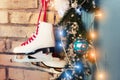 Pair of white vintage leather skates with red laces hanging on old rustic brick wall with glowing garland lights on Royalty Free Stock Photo