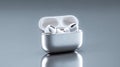 A pair of white wireless earbuds in a silver charging case with the lid open on top of a reflective surface Royalty Free Stock Photo
