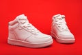 pair of white youth sneakers on red background close-up