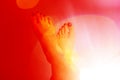 A pair of the woman`s foot on a red color background with halo-effect