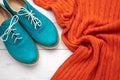 Pair of womens aqua oxfords and orange pullover on white wooden background. Flat lay, casual trendy style concept. Fashion clothes Royalty Free Stock Photo