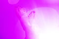 A pair of the women`s foot on a pink color background with a round halo-effect lights