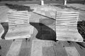 A pair of wooden benches on the sidewalk with long ones in black and white.