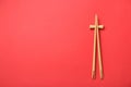 Pair of wooden chopsticks with rest on red background, top view. Space for text Royalty Free Stock Photo