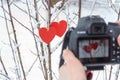 Pair of wooden red hearts on snowy tree with reflection in camera screen. Photography hobby concept. Love and romantic concept.