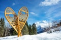 Pair of wooden snowshoes in snow over forest and mountain peaks