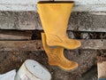 a pair of yellow boots on a piece of wood and the bottom of the bucket is white and circular on the ground. behind it brick wall Royalty Free Stock Photo