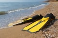 Pair of yellow flippers on sand near sea, closeup Royalty Free Stock Photo