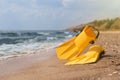 Pair of yellow flippers on sand near sea. Space for text Royalty Free Stock Photo