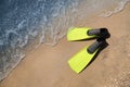 Pair of yellow flippers on sand near sea, top view. Space for text Royalty Free Stock Photo