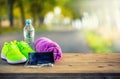 Pair of yellow green sport shoes towel water smart pone and headphones on wooden board. In the background forest or park trail. Royalty Free Stock Photo