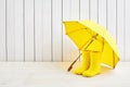 A pair of yellow rain boots and a umbrella on white wooden background Royalty Free Stock Photo