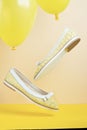 Pair of yellow summer leather female shoes flying on yellow balloons on a yellow background Royalty Free Stock Photo