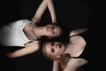 Pair of young women is lying on the floor on the black background
