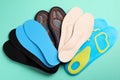 Pairs of different shoe insoles on turquoise background, flat lay