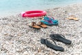 Pairs of flip flop sandals lying on on sea pebble beach