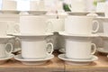 Pairs of mugs and plates on shelf of the tableware store. A lot of rows of pure white cups with plates for coffee break Royalty Free Stock Photo