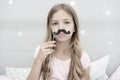 Pajamas party concept. Girl fake mustache at pajamas party. Cheerful kid posing mustache. Photo booth props ideas