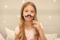 Pajamas party concept. Girl fake mustache at pajamas party. Cheerful kid posing mustache. Photo booth props ideas