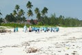 Muslim pupils in uniforms on their way to school over wonderful white beach along palm trees