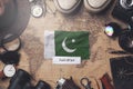 Pakistan Flag Between Traveler`s Accessories on Old Vintage Map. Overhead Shot