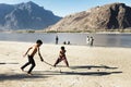 Pakistani kids play hockey with improvised wooden sticks on sand along Indus river, Skardu, Pakistan