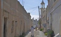 Pakistani man walking on an unpaved street and mosque in an old district of Doha, Qatar