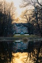 Palace in Pawlowice park at sunset reflected in small lake