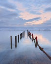 Palafitic pier submerged at sunset whit red rope and pink sky