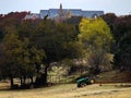 Palatial house almost hidden in trees on hill with country pasture and fence and tractor in foreground Royalty Free Stock Photo