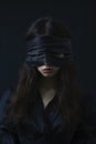 A pale, dark haired young woman in a gothic dress, with blindfolds covering both her eyes Royalty Free Stock Photo