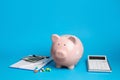 Pale pink ceramic piggy bank, clipboard and calculator on light blue background. Medical insurance Royalty Free Stock Photo