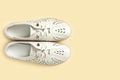 Pale white female shoes on yellow backdrop. Flat lay, top view trendy fashion feminine background