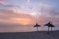 Three thatched beach umbrellas on deserted beach during winter sunset Royalty Free Stock Photo