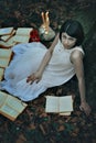 Pale woman and books in a dark forest