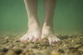 Feet underwater on stoney and muddy ground Royalty Free Stock Photo